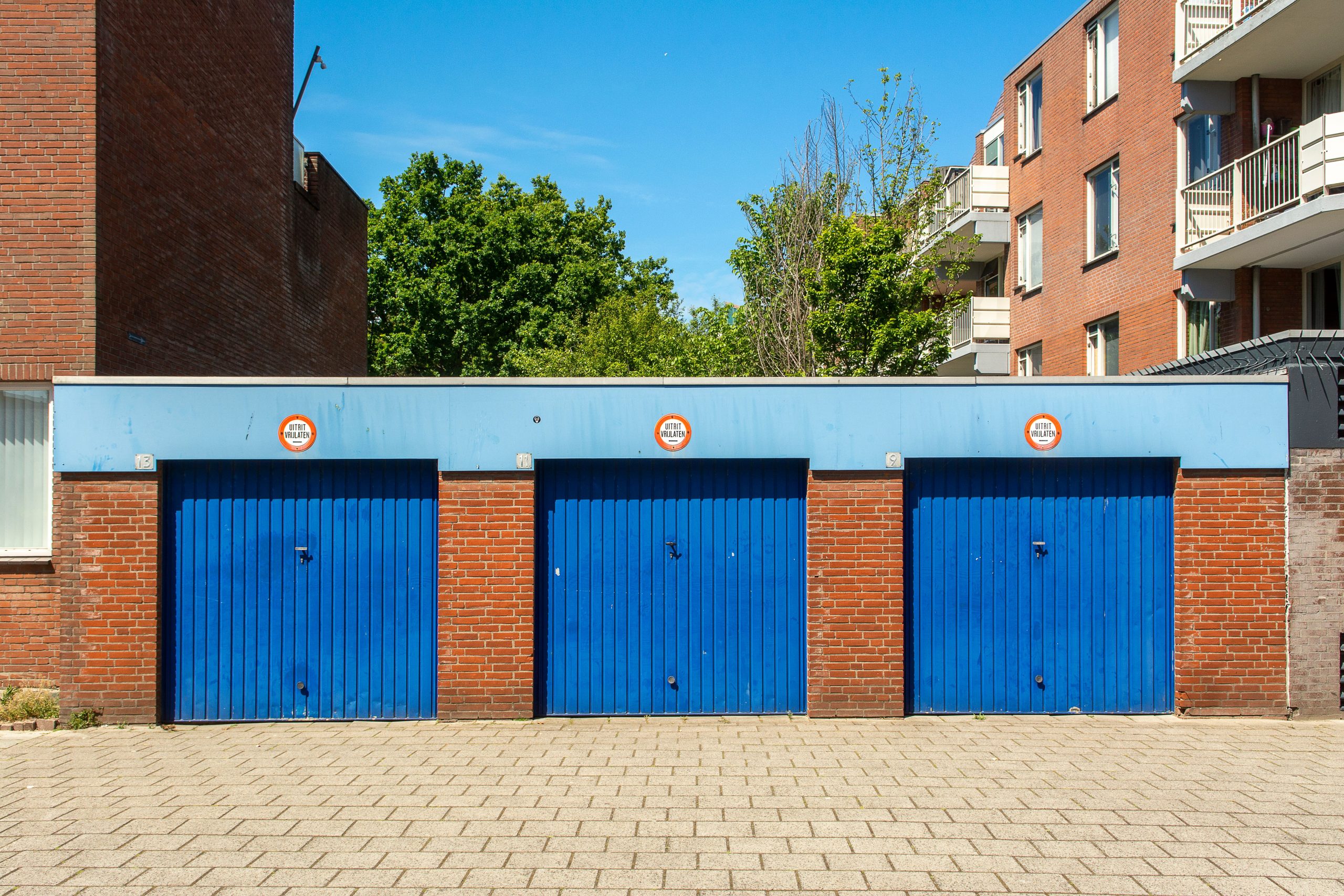 Trois portes garage bleues bâtiment brique