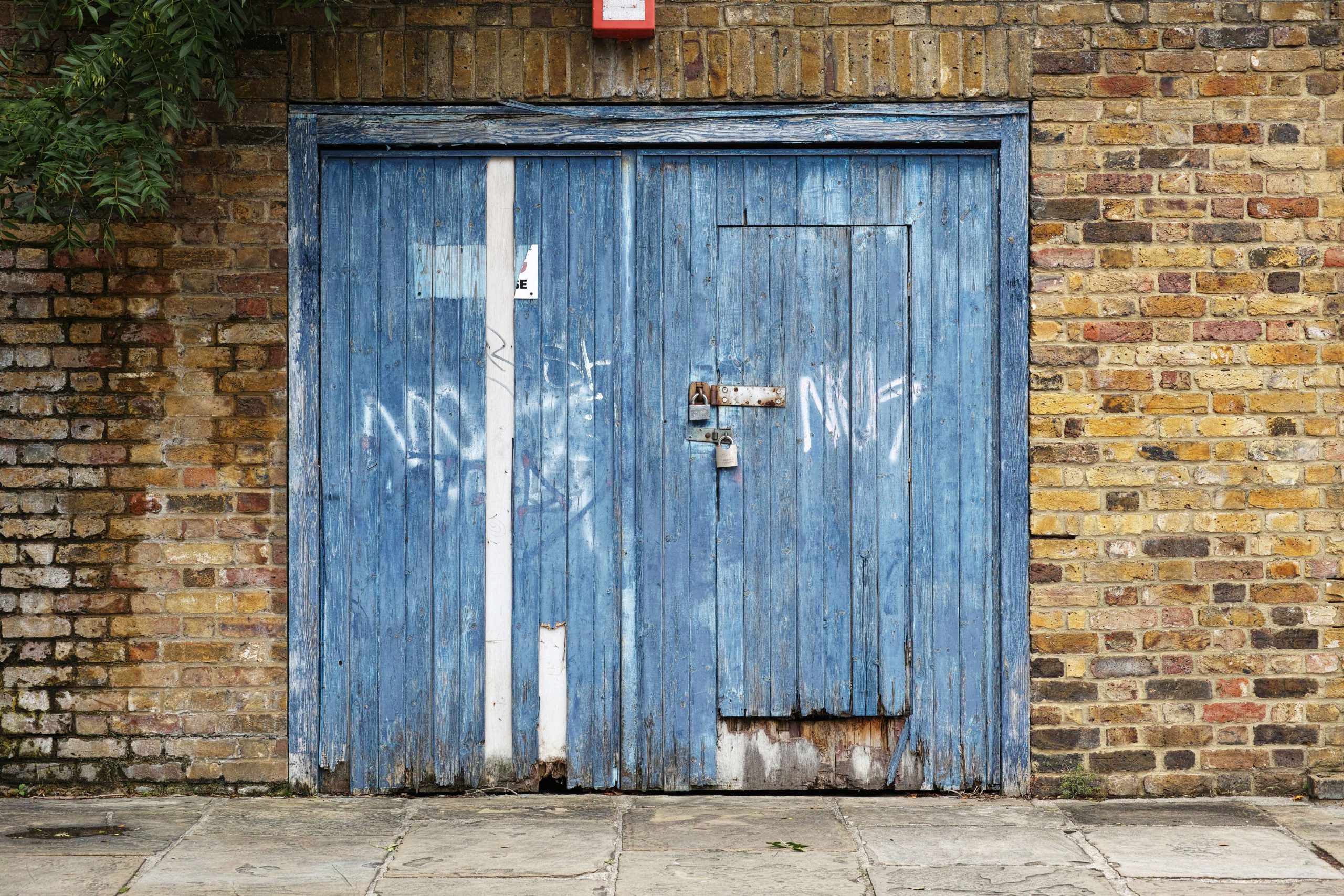 Porte garage bois bleu sur mur brique